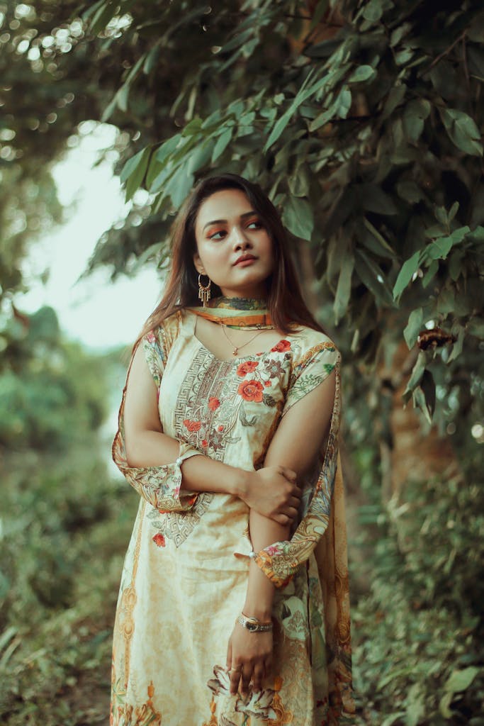 Portrait of a woman in an elegant floral dress standing outdoors in nature.